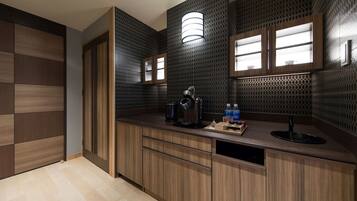 A modern kitchen with wooden cabinets, a built-in sink, and a countertop with a kettle and bottles.