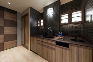 A modern kitchen with wooden cabinets, a built-in sink, and a countertop with a kettle and bottles.