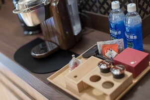 Una bandeja de madera con bolsitas de té, un vaso y una caja roja sobre una mesa.