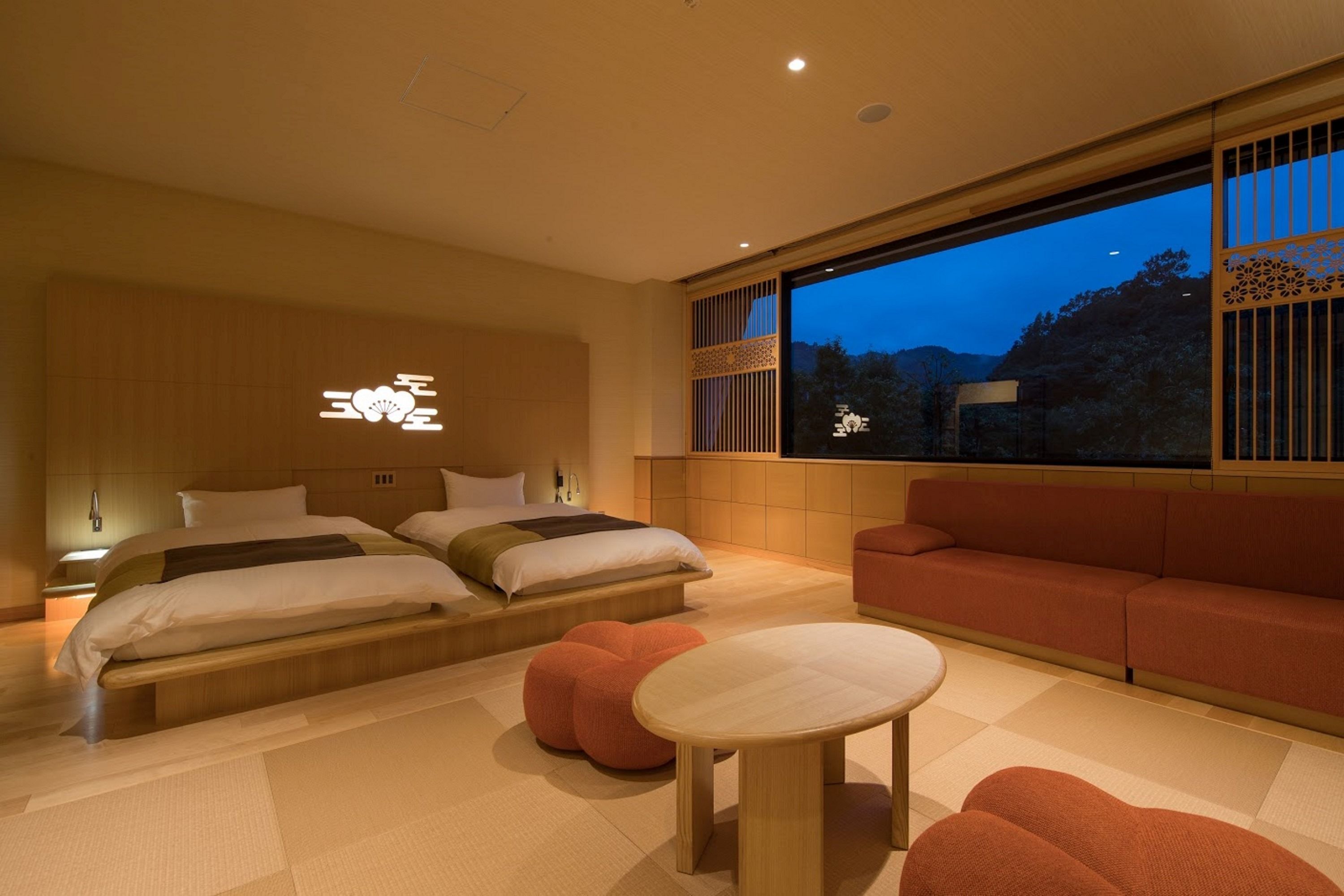 A modern hotel room with a large bed, a sofa, and a dining table.