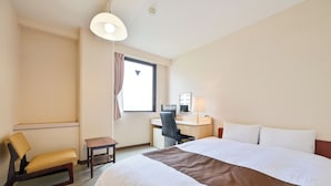 Une chambre d’h ôtel avec un grand lit, un bureau avec une chaise, une petite table et une fenêtre avec des rideaux.