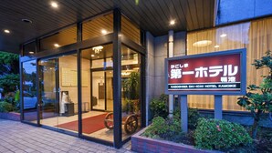 L’entrée d’un hôtel, avec une porte en verre, une enseigne et un tapis rouge menant à l’intérieur.
