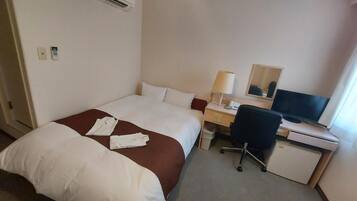 Una habitación de hotel con una cama, un escritorio con computadora, una silla y un televisor.