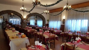 A banquet hall with multiple round tables set for dining, each with white tablecloths and red napkins. - Albergo Ristorante Poli (San Benedetto Val di Sambro)