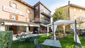 An outdoor patio area with tables and chairs, a covered seating area, and a building with a restaurant sign. - Albergo Ristorante Poli (San Benedetto Val di Sambro)
