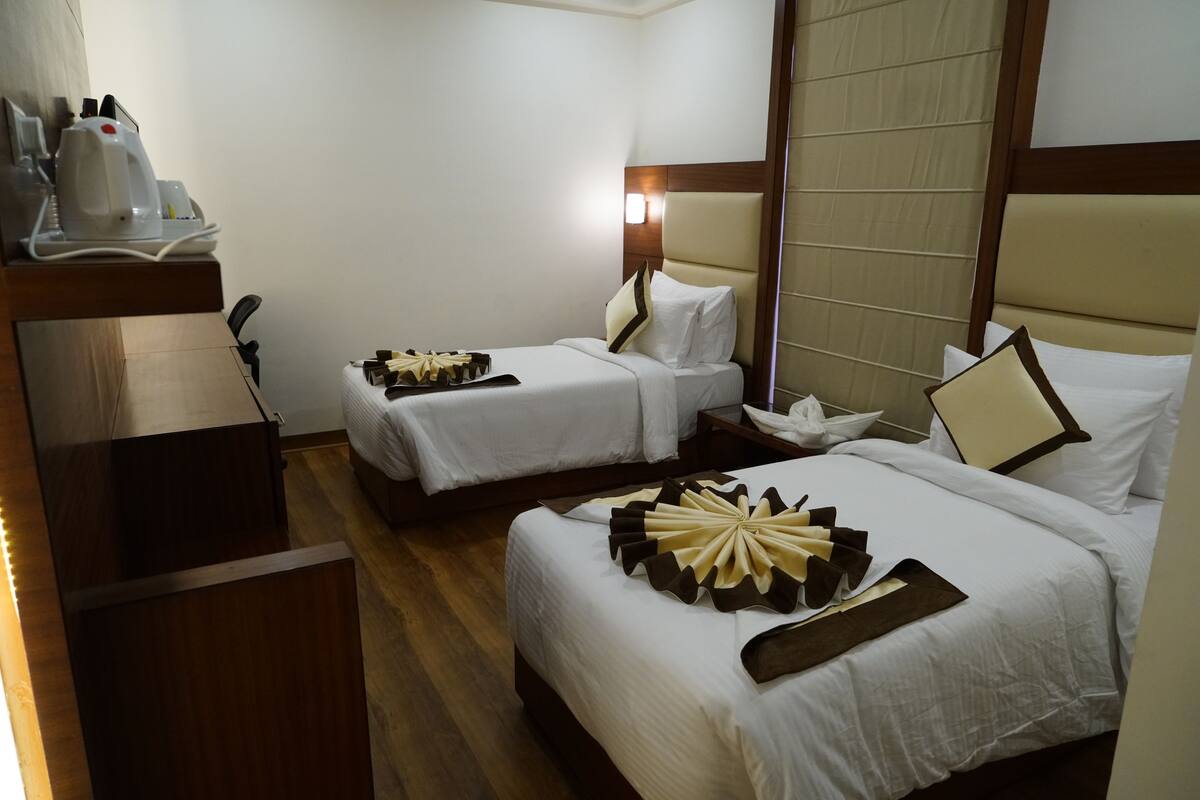 A hotel room with two beds, a desk, and a nightstand.