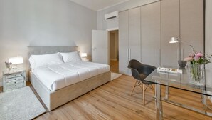 A modern bedroom with a bed, bedside tables, a glass desk, and a wardrobe. - Santa Croce Deluxe (Florence)