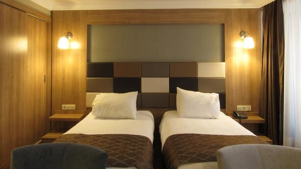 A hotel room with two beds, a wooden headboard, bedside lamps, and a small table. - Kadıköy Park Suites (Istanbul)