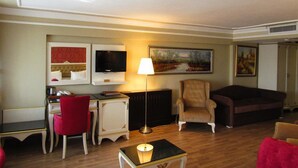 A living room with a desk, a red chair, a beige armchair, a dark sofa, and a lamp. - Kadıköy Park Suites (Istanbul)