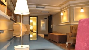 A hotel lobby with a sofa, a table, and a lamp. There is a door leading to another room. - Kadıköy Park Suites (Istanbul)