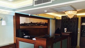 A reception desk with a cityscape painting, a chandelier, and a wooden panel design. - Kadıköy Park Suites (Istanbul)