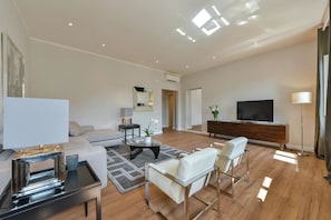 Un salon moderne avec un canapé, une table basse, un téléviseur et une lampe sur pied.
