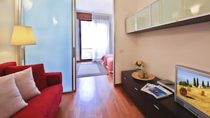 Een moderne woonkamer met een rode bank, een televisie en een tijdschrift op een zwart kastje.