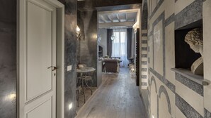 A hallway with a dining area, a chandelier, and a decorative wall. - Signoria Art (Florence)