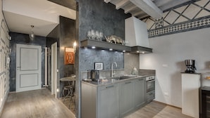 A modern kitchen with a central island, built-in oven, and stainless steel appliances. - Signoria Art (Florence)