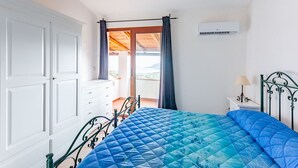 A bedroom with a bed, a dresser, an air conditioning unit, and a view of the outdoors. - Comino Alto Agriturismo e  Appartamenti (Siniscola)