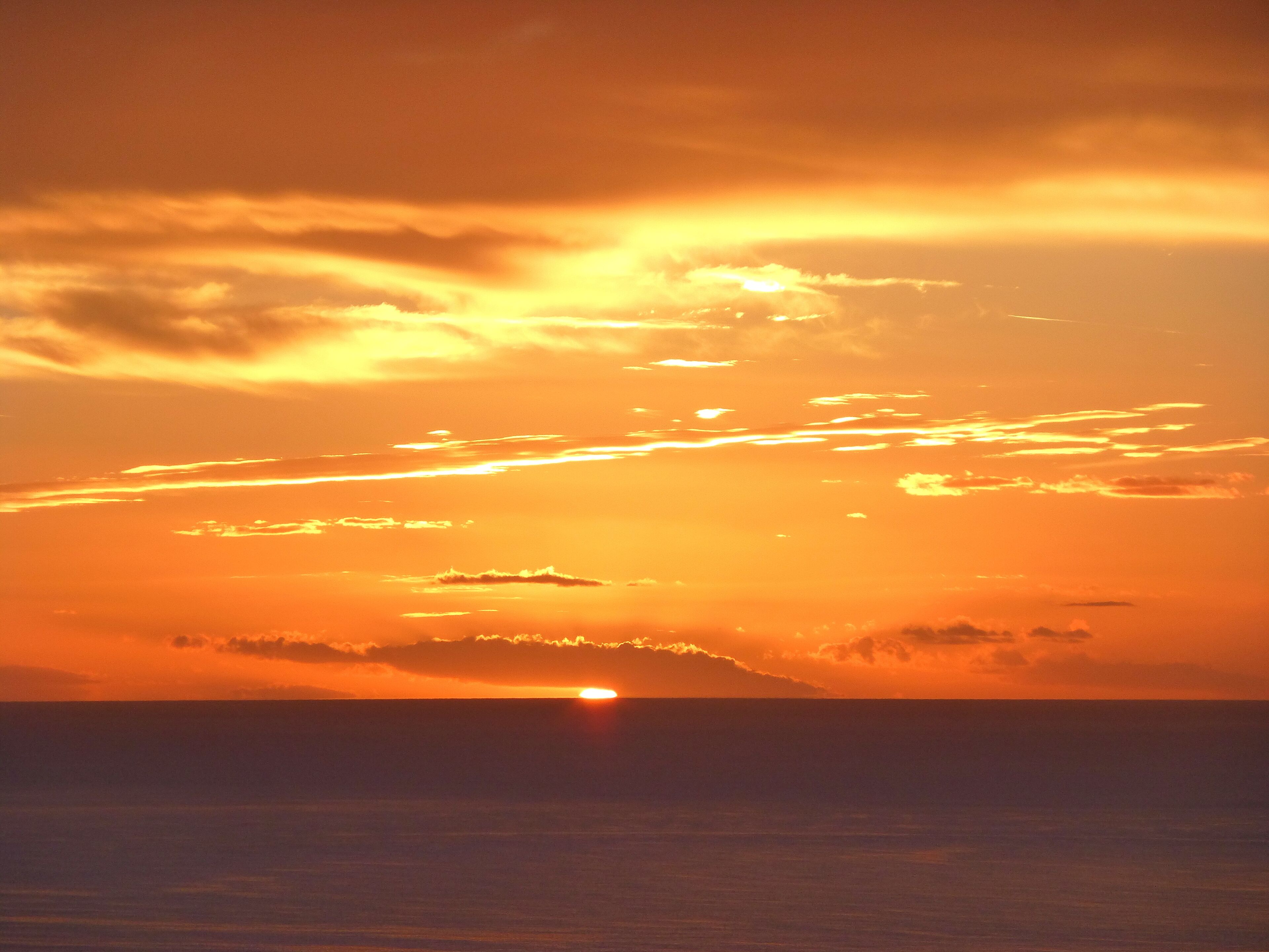 Um pôr do sol sobre o oceano, com horizonte límpido.
