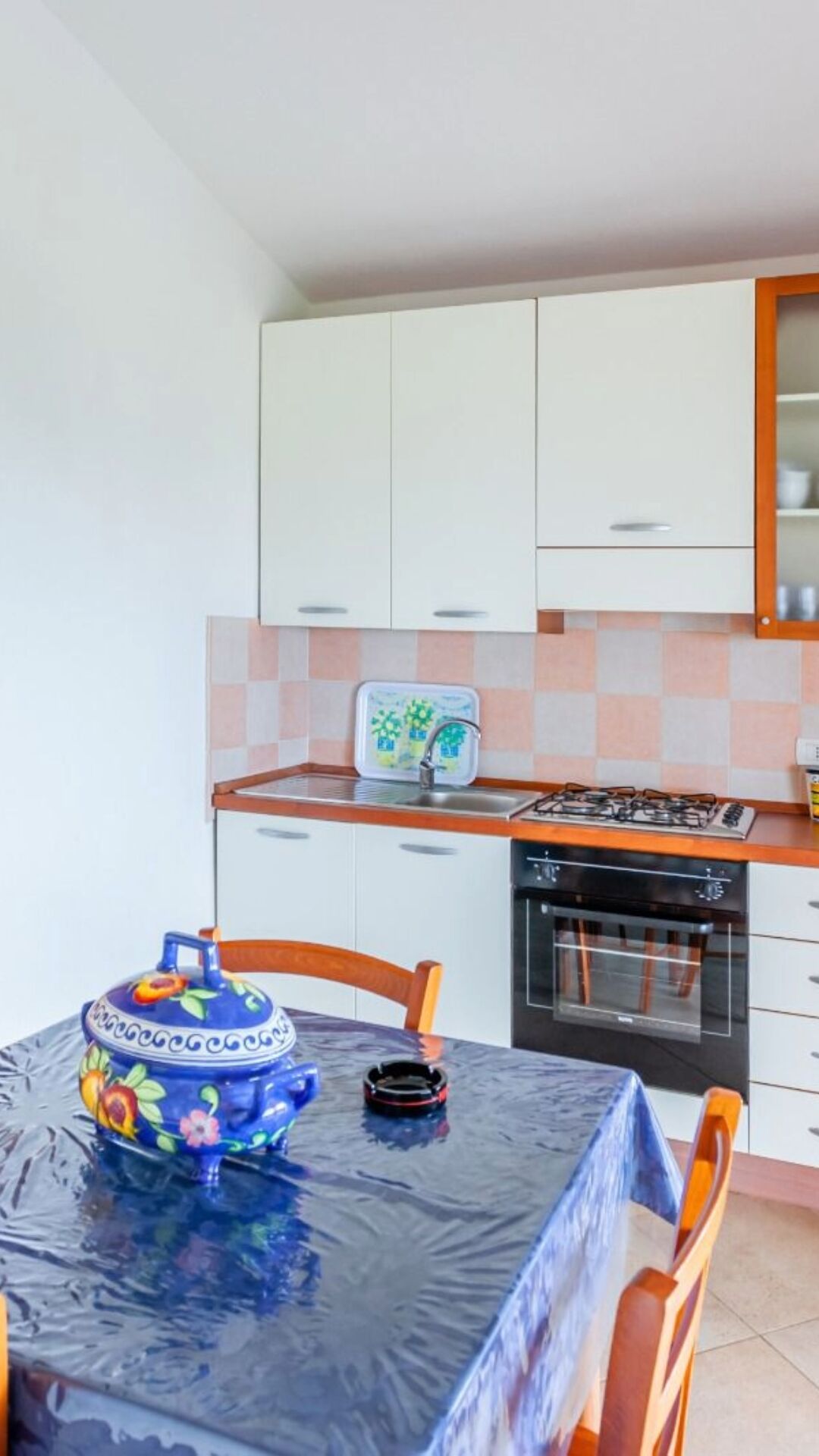 Een kleine keuken met een eettafel, stoelen, een fornuis en een vaatwasser.