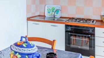 Een kleine keuken met een eettafel, stoelen, een fornuis en een vaatwasser.