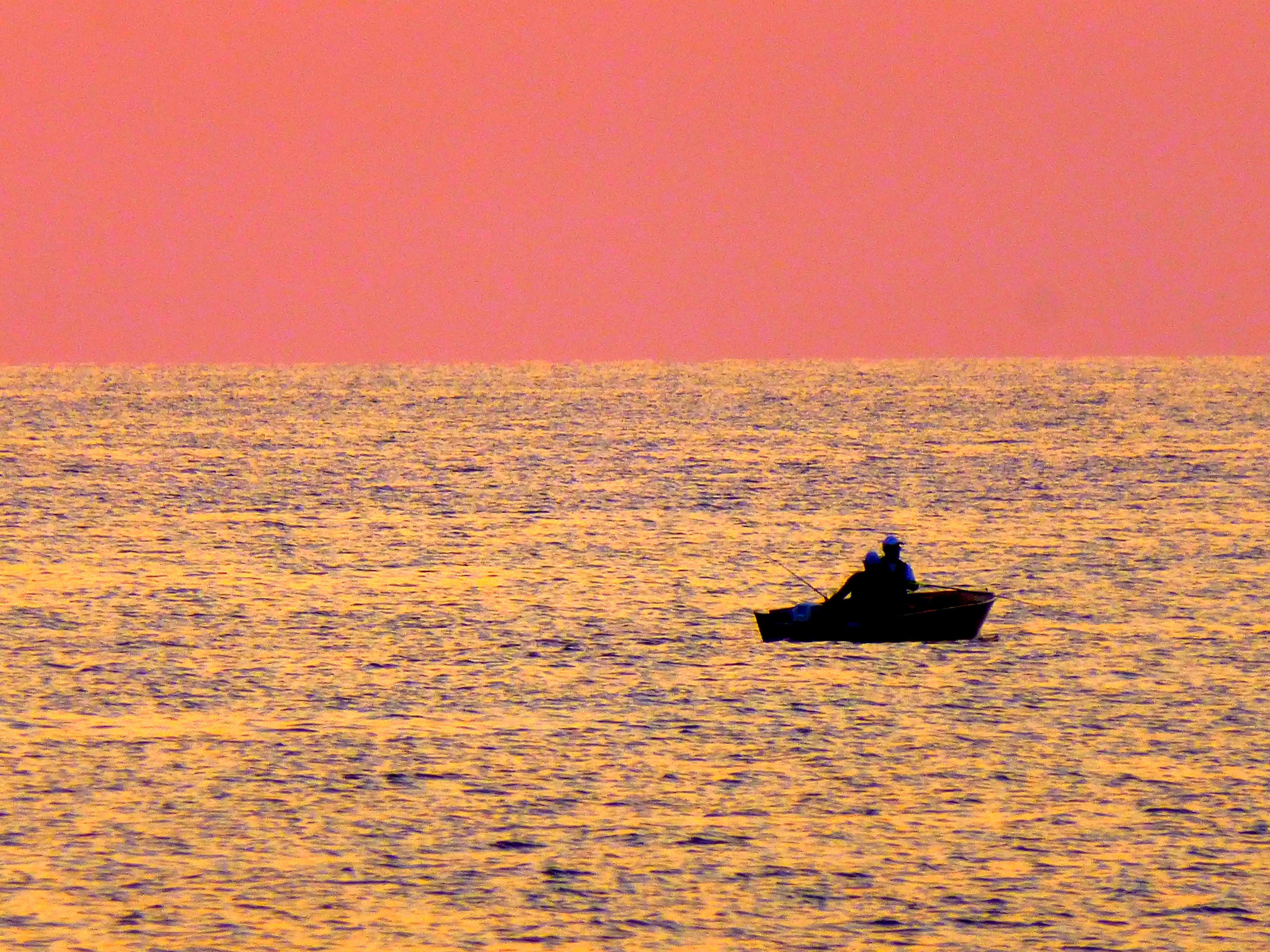 Ein Boot auf ruhigem Wasser, der Himmel in Rosa.