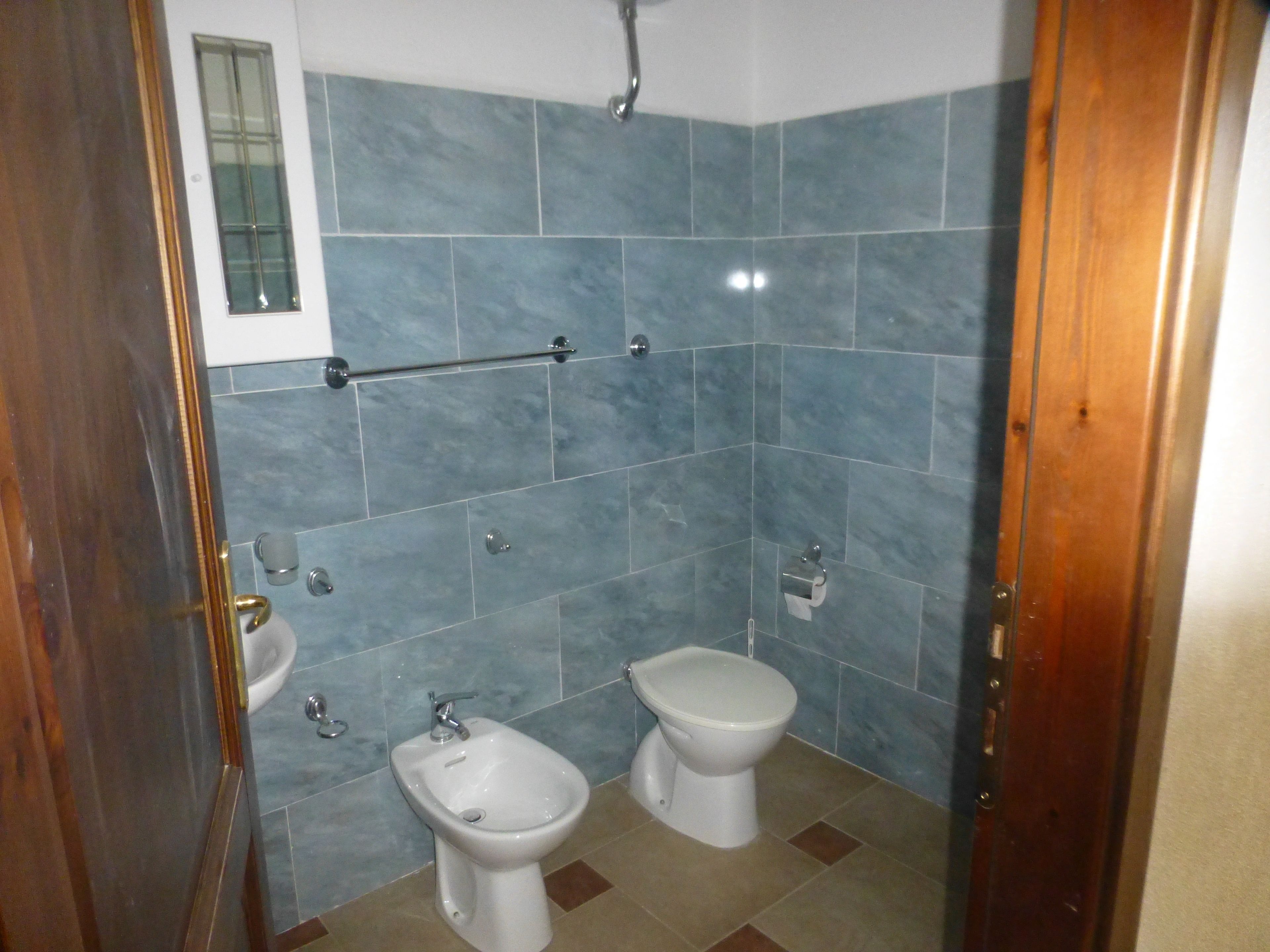 A bathroom with two toilets, a bidet, and a hand basin.