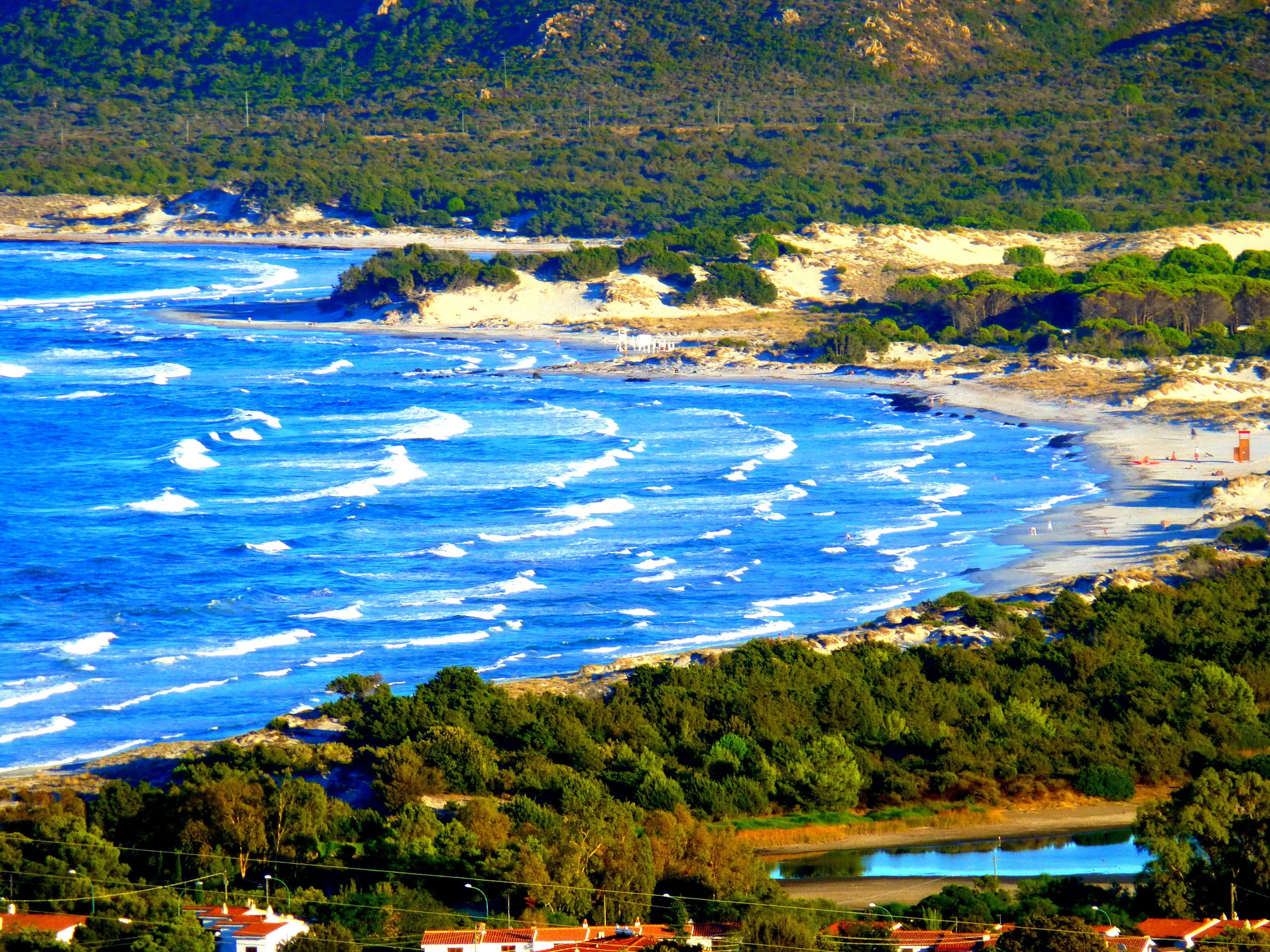 Un paysage côtier comprenant une plage, une côte rocheuse et une végétation luxuriante.