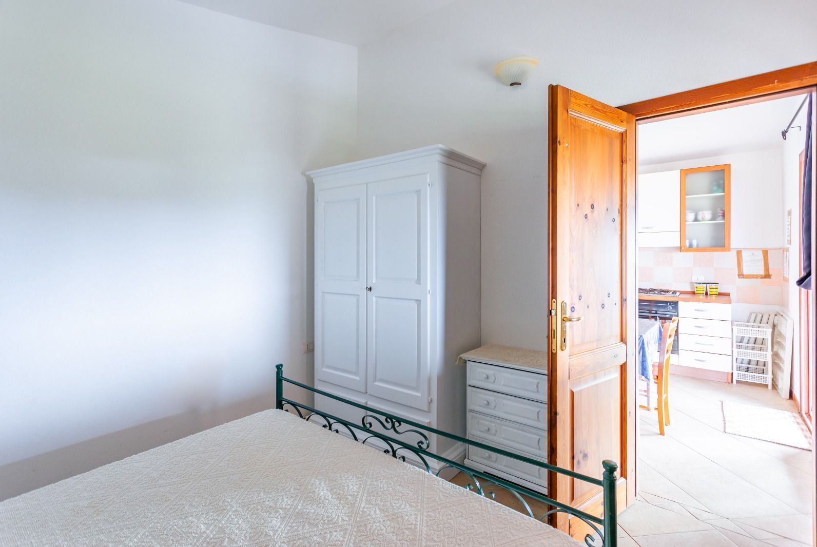 A bedroom with a bed, a wardrobe, and a door leading to a bathroom.