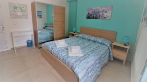 A bedroom with a bed, a desk, a mirror, and a nightstand. - B&B La Rosatea (Monreale)