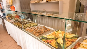 A buffet with various food items including pastries, fruits, and vegetables.