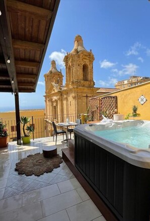 A hot tub and patio area with a view of a church and ocean. - B&B Rabaté (Agrigento)