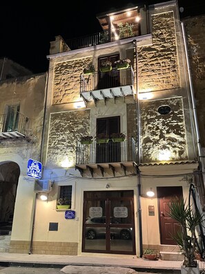 A two-story building with a ground-floor bar and a second-floor balcony with plants. - B&B Rabaté (Agrigento)