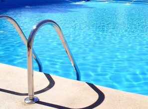 Een zwembad met helderblauw water en metalen zwemtrap.