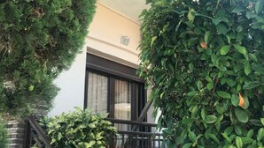 Een gebouw met twee verdiepingen, een balkon, een trap en diverse groene planten.