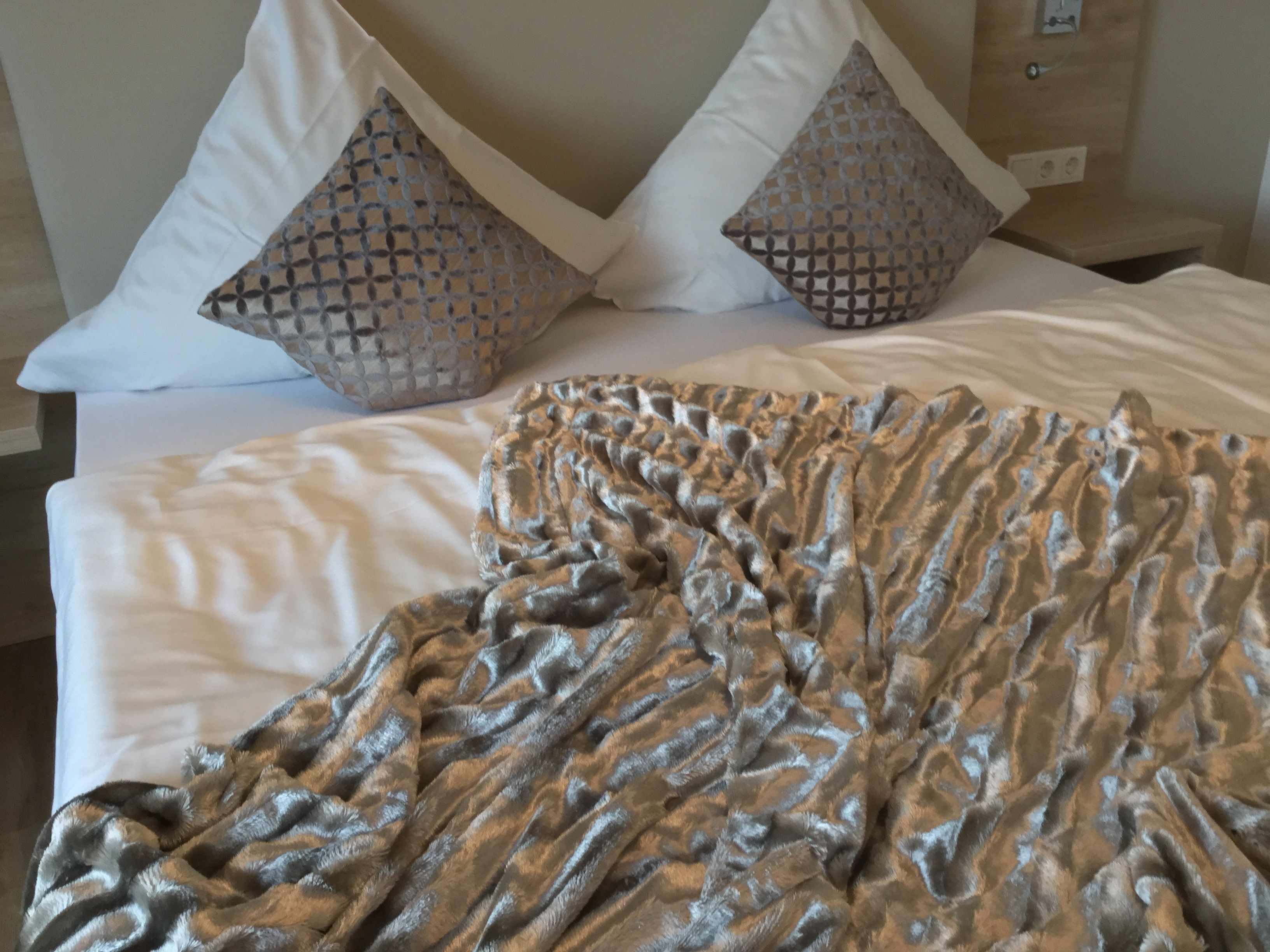 Una cama bien hecha con un edredón estampado y dos almohadones decorativos.