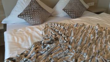 Una cama bien hecha con un edredón estampado y dos almohadones decorativos.