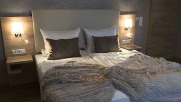 A neatly made bed with two pillows, a fluffy blanket, and two bedside lamps on wooden nightstands.