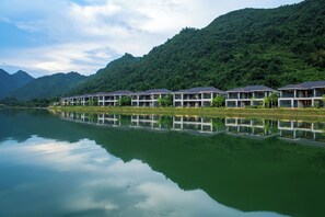 A row of waterfront hotel buildings with balconies, reflecting on the calm water. - Lanshanyuan LN Dongfang Hotspring Resort (Shaoguan)