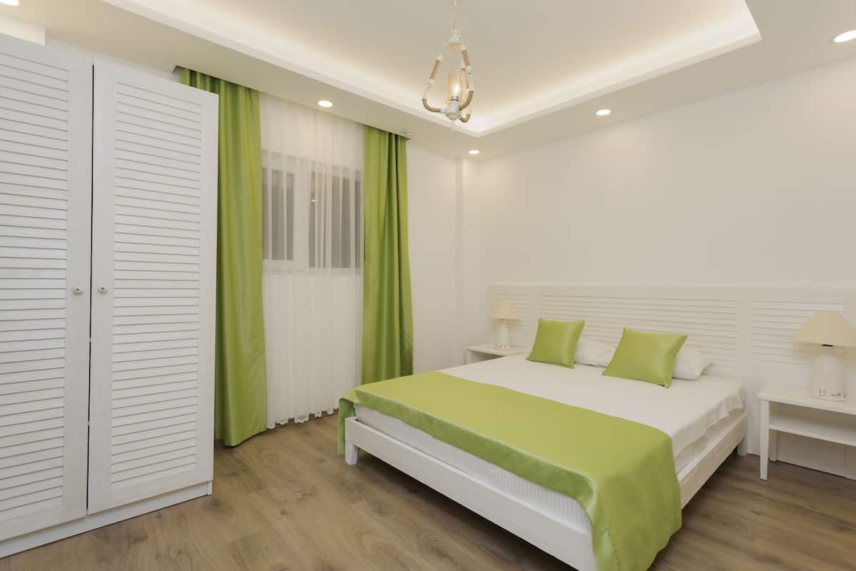 A bedroom with a bed, bedside tables, a wardrobe, and a chandelier.