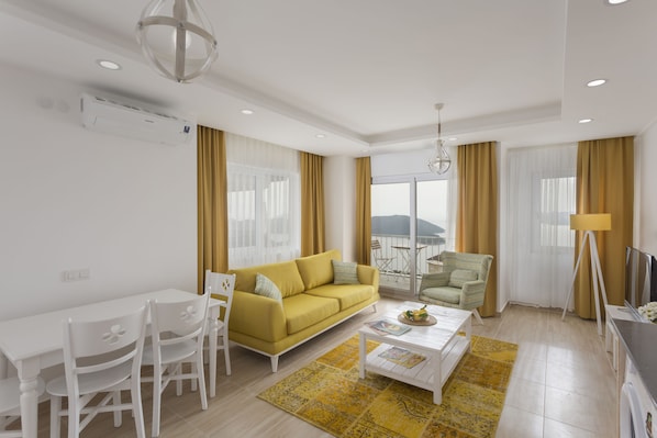 A modern living room with a yellow sofa, white chairs, a coffee table, and a TV.