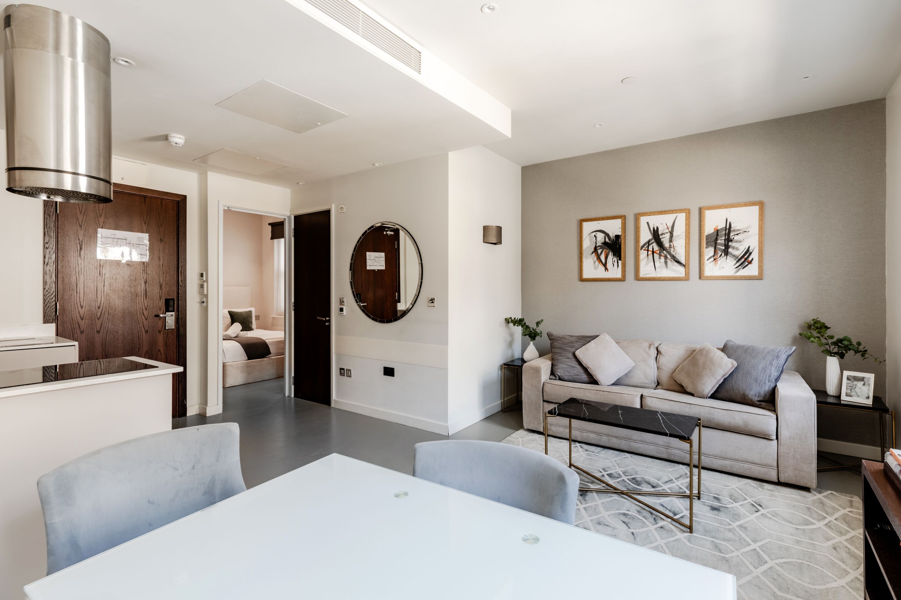 A modern living room with a sofa, a dining table, and a kitchen area with a stove.