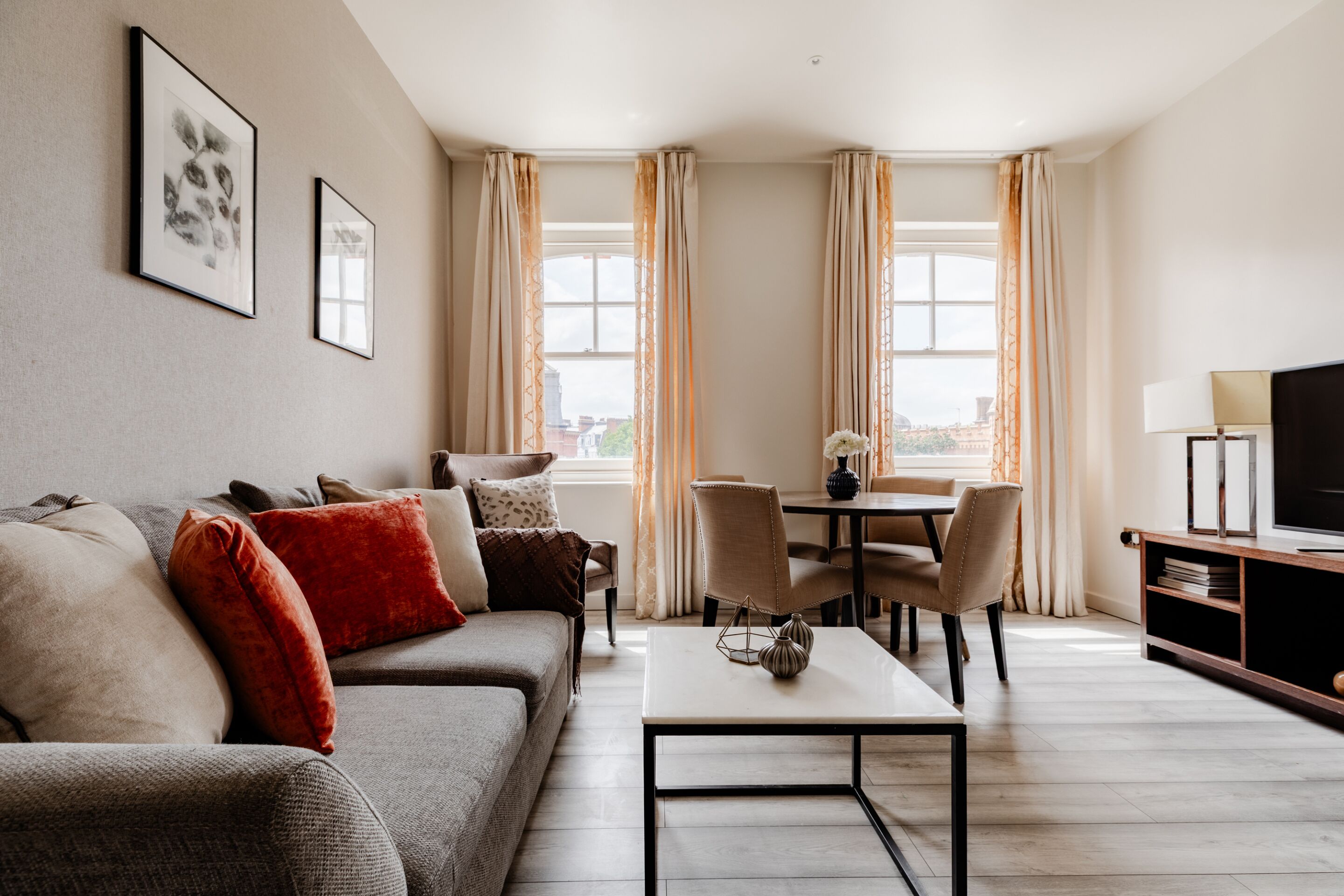 A modern living room with a sofa, a coffee table, and a dining area with chairs and a table.