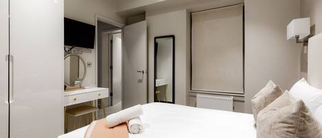 Une chambre d’hôtel comprenant un lit, un bureau avec un miroir, une armoire et un radiateur.