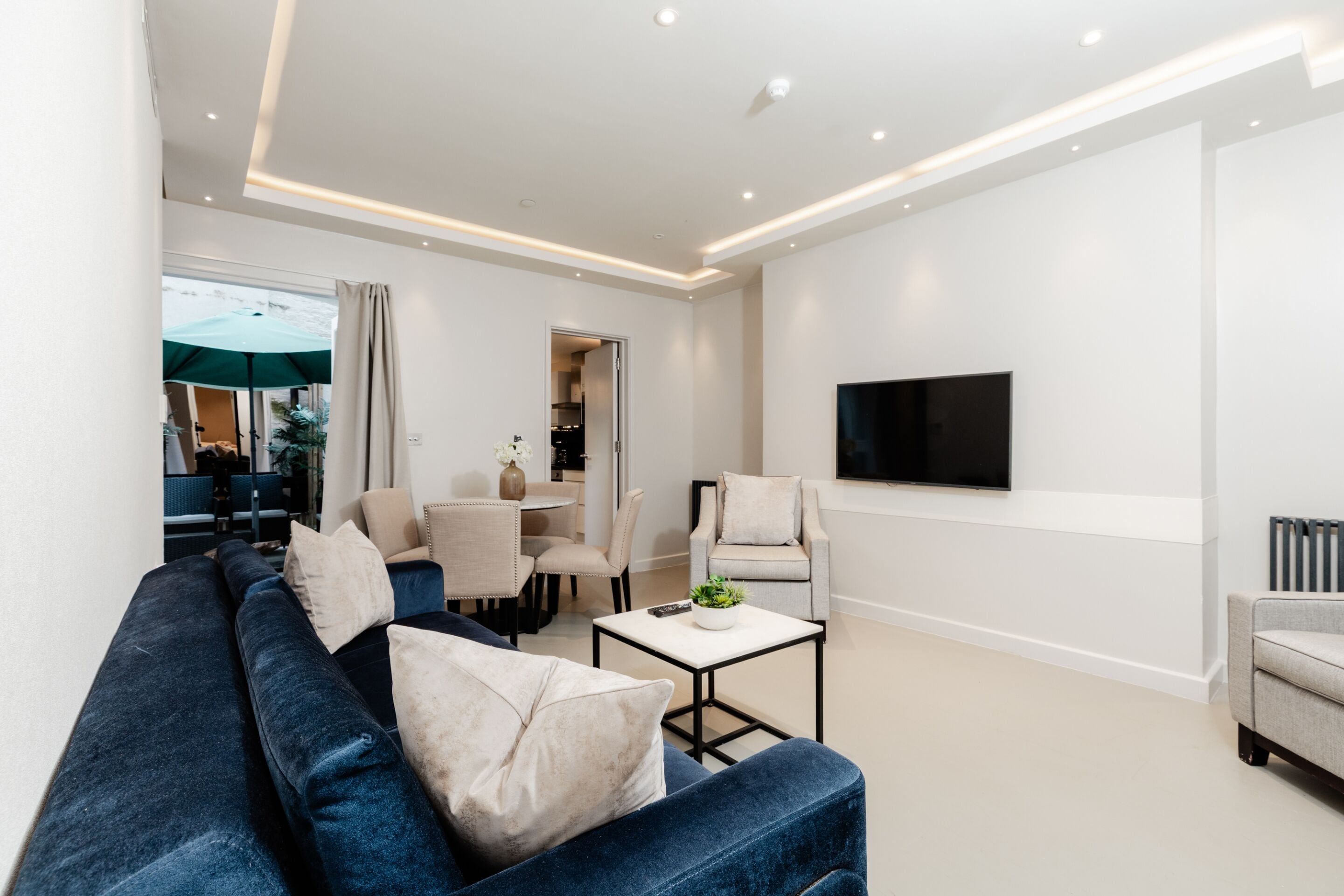 A modern living room with a blue sofa, a coffee table, and a TV mounted on the wall.