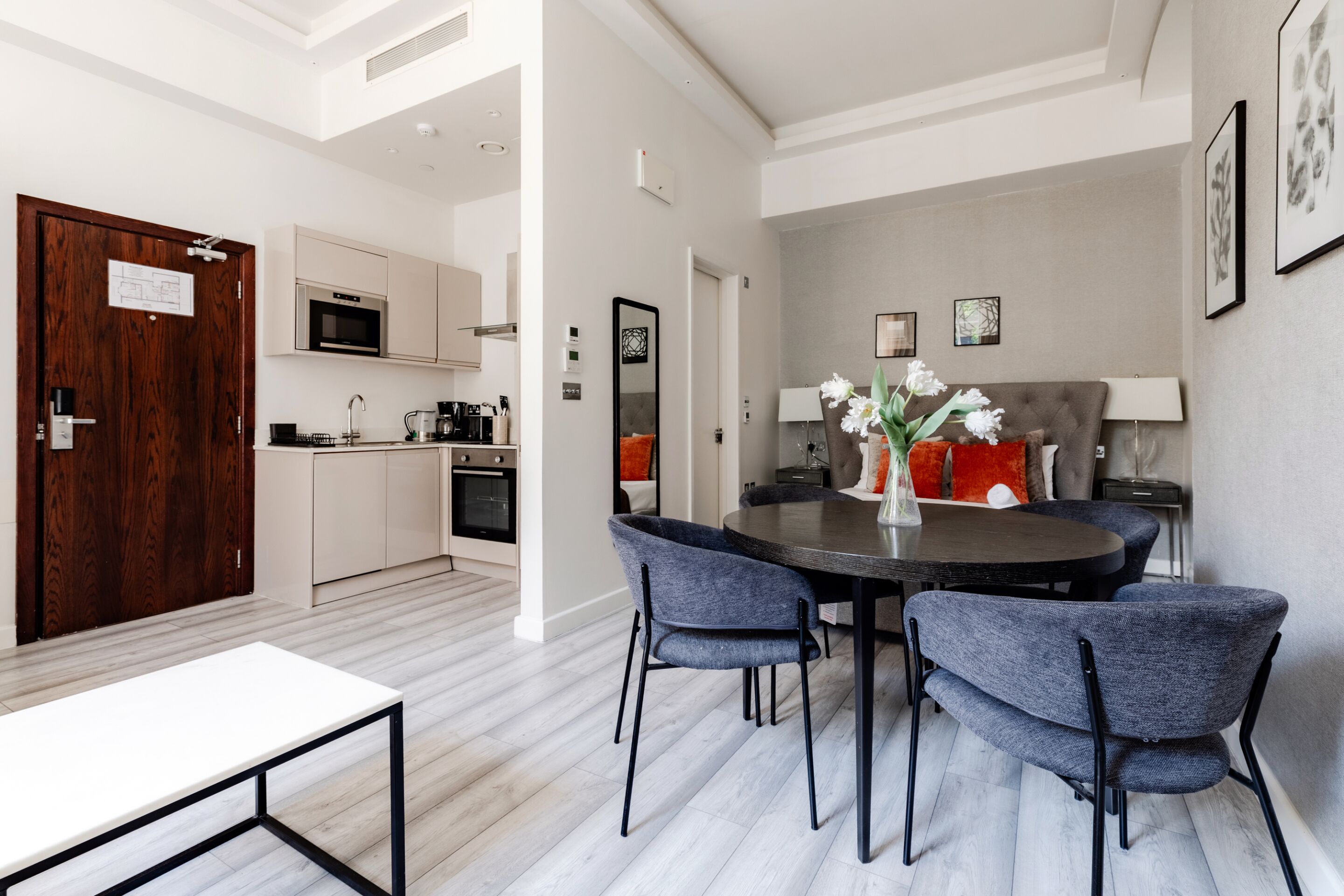 A modern kitchen with a microwave, oven, and coffee maker. There is a dining area with a round table and four chairs.