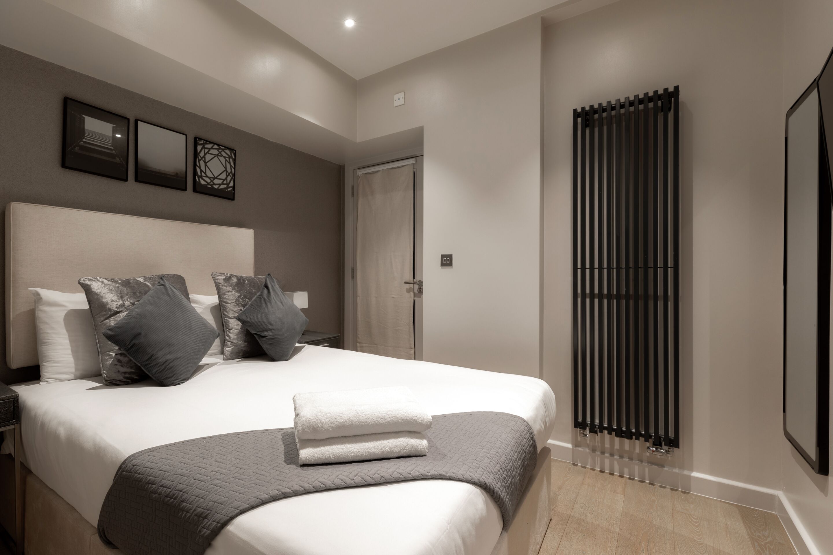 A modern bedroom with a large bed, a bedside table, and a radiator.