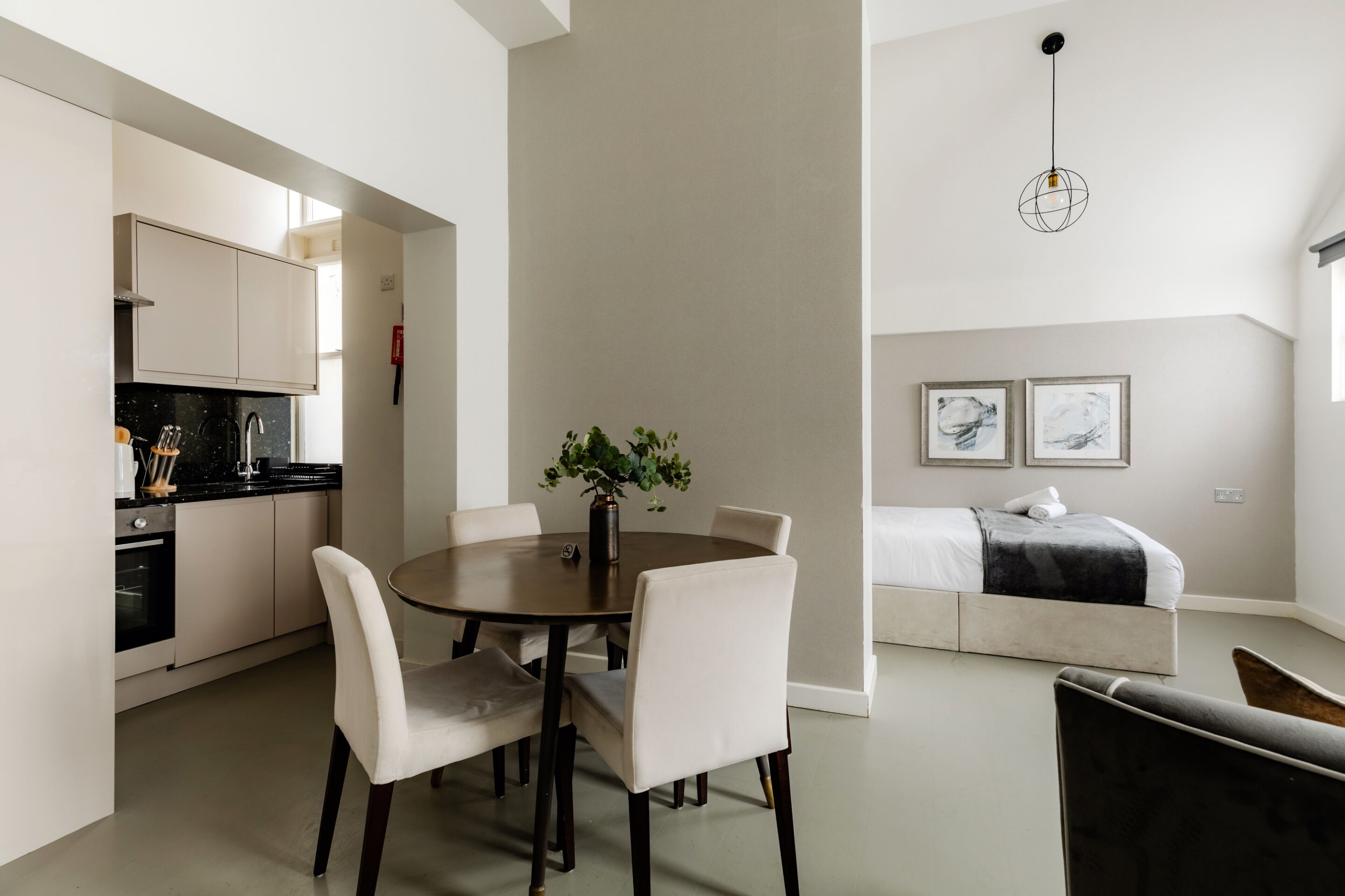 A modern apartment with a dining area, kitchen, and a bedroom.