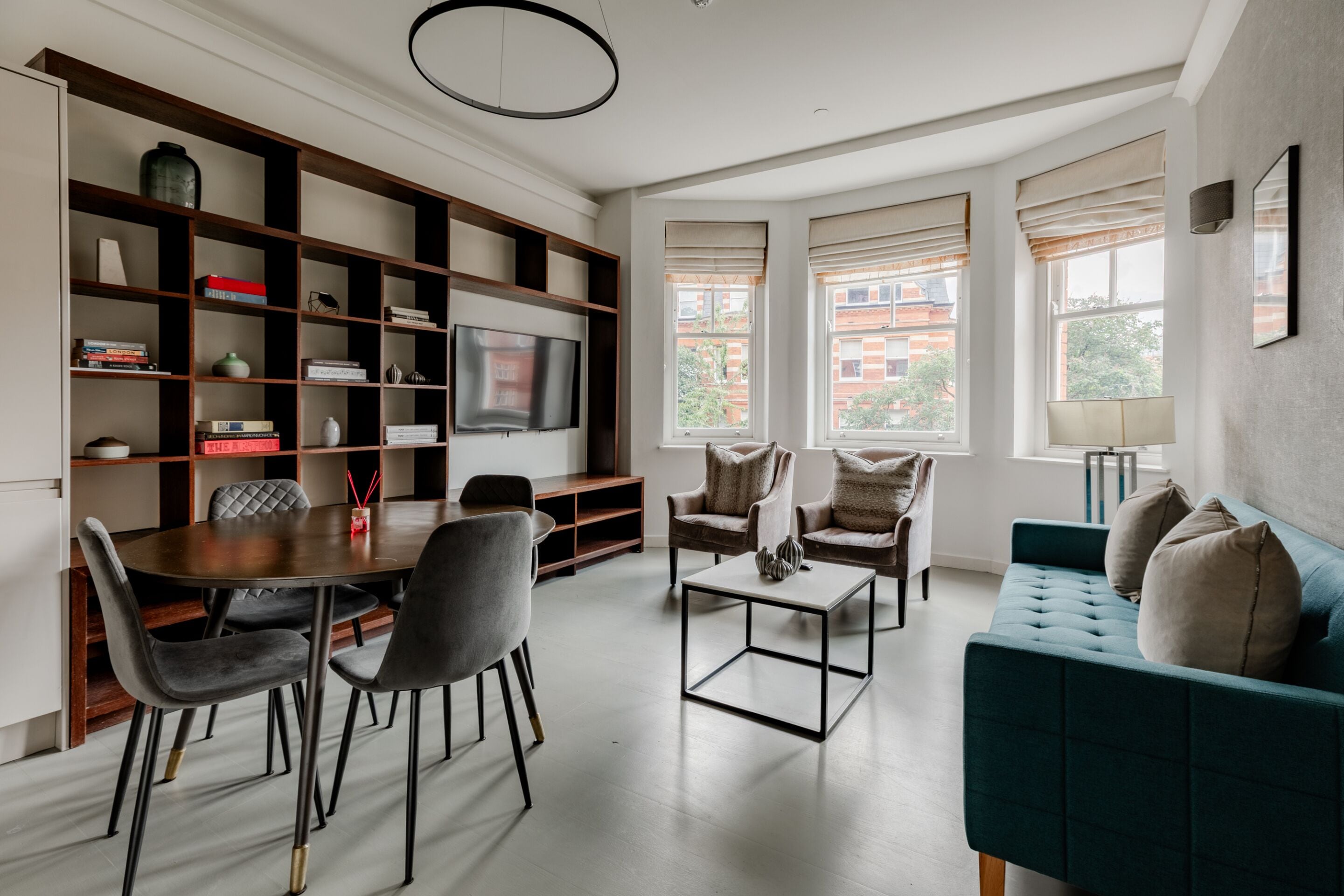 A modern living room with a dining area, a television, and a sofa.