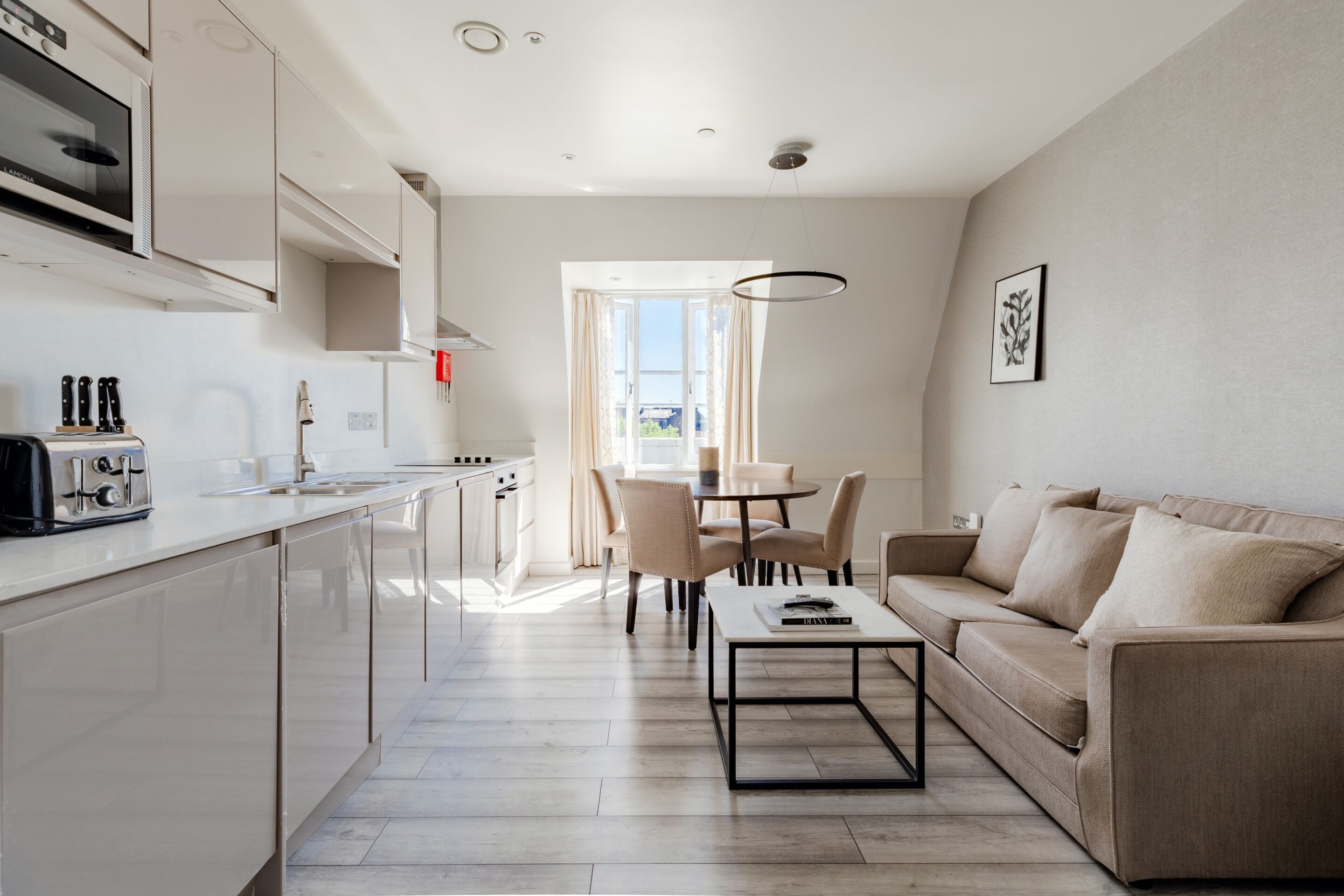 A modern kitchen with a dining area, a sofa, and a coffee table.