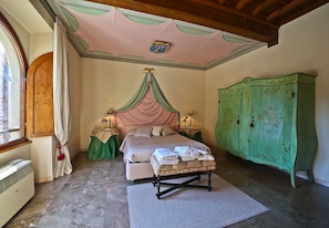Une chambre à coucher avec un lit à baldaquin, une armoire verte et une fenêtre avec des rideaux.