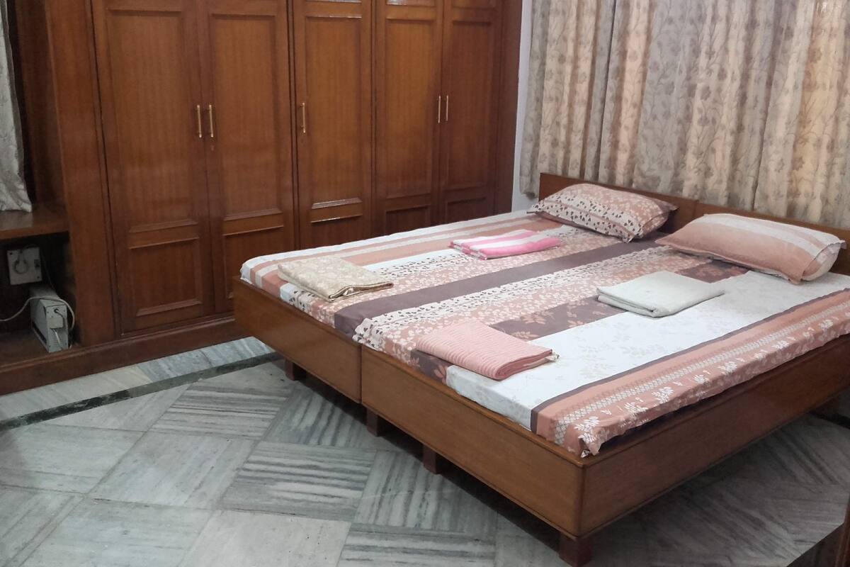 Une chambre à coucher avec un lit en bois, une armoire et un rideau à motifs.